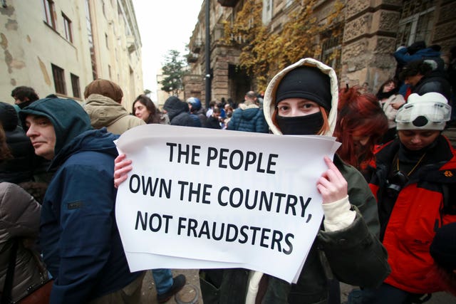 A protester holds a poster as they gather in a street during a rally to demand new parliamentary elections in the country, near the Parliament’s building in Tbilisi, Georgia 