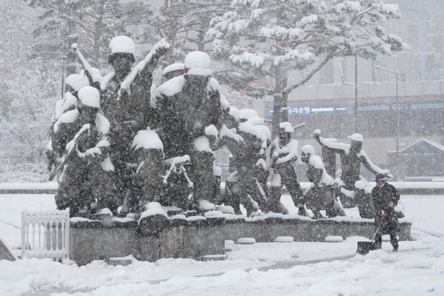 A worker shovels snow near a monument in remembrance at the Korea War Memorial Museum in Seoul