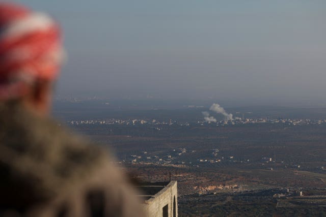 An observer watches as smoke rises amid fighting between opposition factions and Syrian government troops in Majdaliya