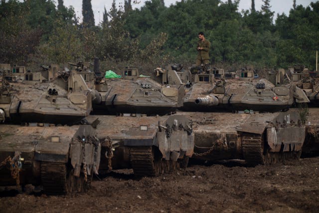 An Israeli soldier stands on the top of a tank on an area near the Israeli-Lebanese border