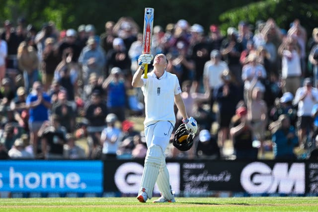 Harry Brook celebrates by raising his bat after scoring a century