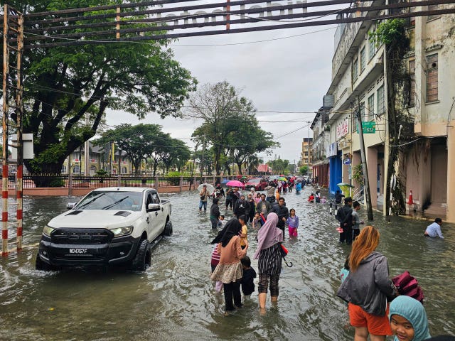 Residents walk along a flooded street in Malaysia