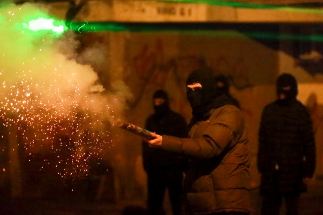 A demonstrator launches a firecracker towards police