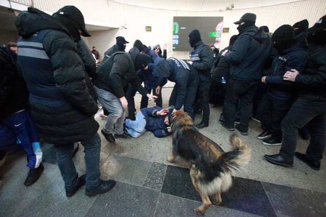 Police officers detain a demonstrator at a subway station