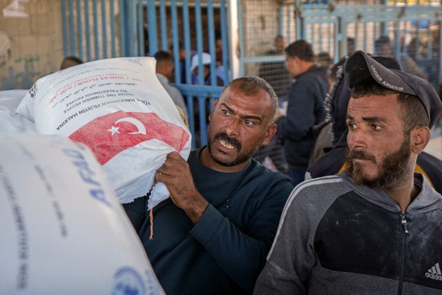 A man grabs a sack of donated flour at a UNRWA distribution center in the Nuseirat refugee camp