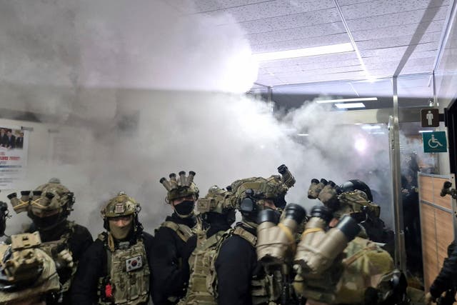 A National Assembly staff member sprays fire extinguishers to block soldiers entering the main hall of the National Assembly in Seoul, South Korea