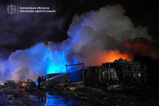 In this photo provided by Zaporizhzhia Military Administration, firefighters extinguish a fire following a Russian attack