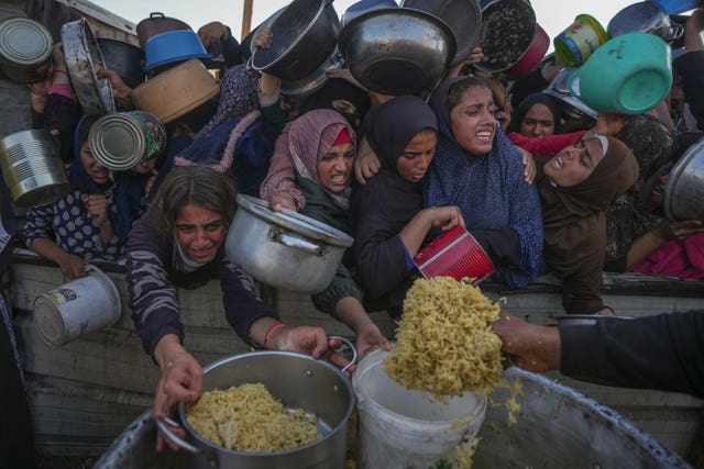 Palestinian girls struggle as they get donated food at a distribution center in Khan Younis, Gaza Strip