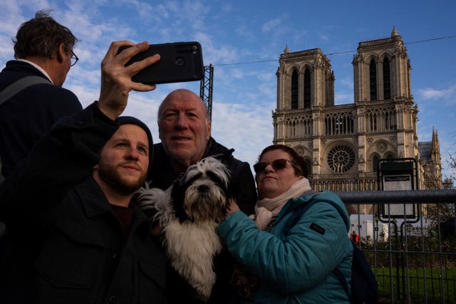 Tourists pose for selfies with the cathedral in the background