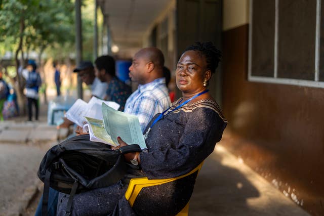 Party observers watch people casting their ballot 