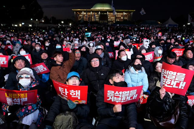 Hundreds of people holding red placards