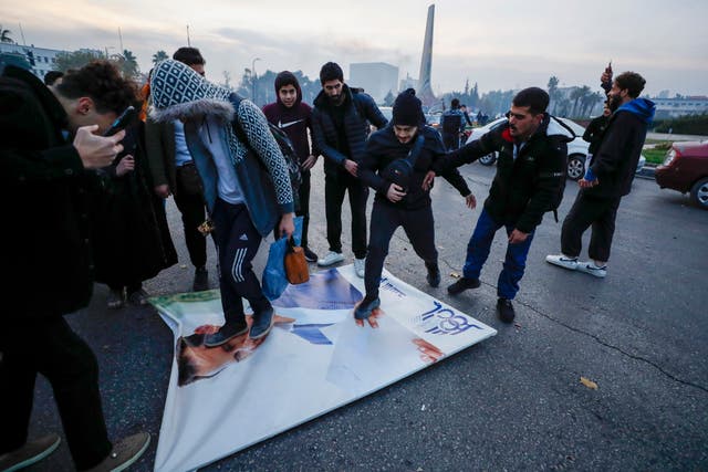 Syrians celebrate the arrival of opposition fighters as they step on a picture of Syrian President Bashar Assad in Damascus 