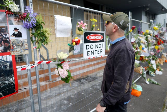 A man reads messages left on the fence outside the fire damaged Adass Israel Synagogue in Melbourne 