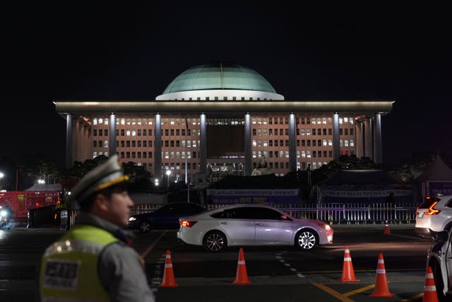 A traffic police officer walks near the National Assembly as a rally demanding South Korean President Yoon Suk Yeol’s impeachment is taking place, in Seou