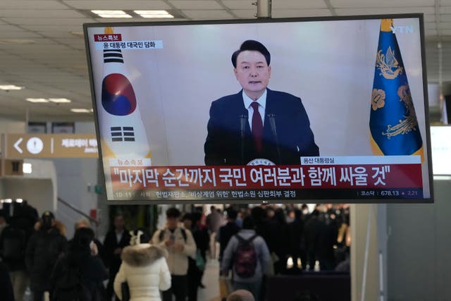 A TV screen shows South Korean President Yoon Suk Yeol’s televised briefing at a bus terminal in Seoul