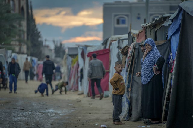 Palestinians stand outside their tents at a camp for displaced people in the Gaza Strip