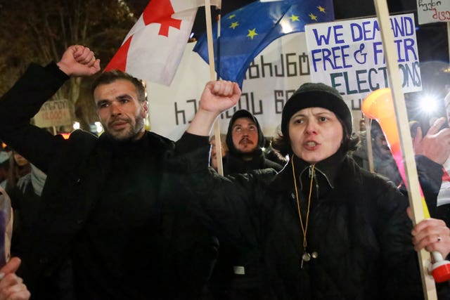 Demonstrators with a Georgian national flag and an EU flag rally outside the parliament to protest against the government’s decision to suspend negotiations on joining the European Union in Tbilis