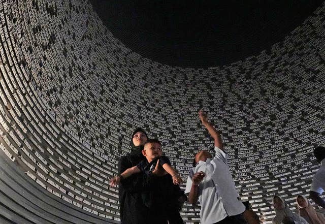 Visitors looks at a wall displaying the names of the victims of 2004 Indian Ocean tsunami, at the Tsunami Museum in Banda Aceh