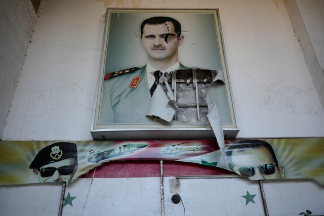 A torn posters shows the late Syrian President Hafez Assad and his son the ousted Syrian president Bashar Assad, that were set at the entrance of the notorious security detention centre called Palestine Branch, in Damascus, Syria