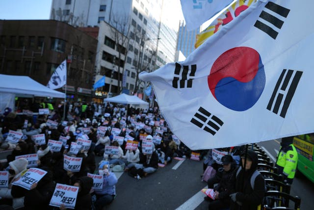 Participants hold signs during a rally calling on the Constitutional Court to dismiss the President Yoon Suk Yeol in Seoul on Sunday