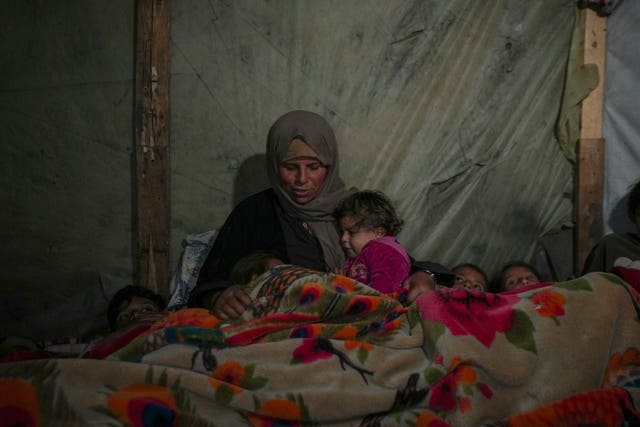 Woman and several small children under blanket