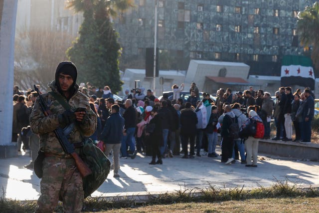 A Syrian fighter stands guard as activists gather at the Umayyad square in Damascus