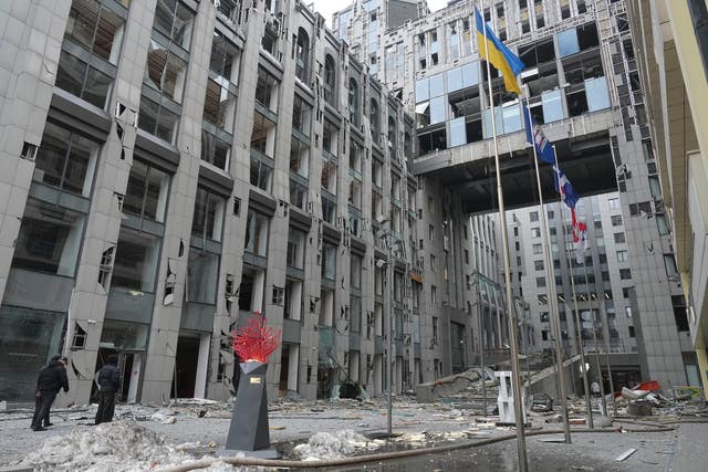 People stand next to buildings destroyed by the recent Russian attacks in Kyiv,