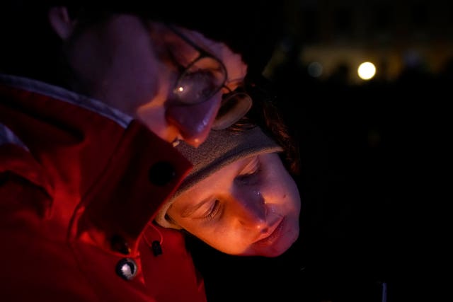 A mourner rests their head on another person's shoulder outside Magdeburg Cathedral during a memorial service for those killed