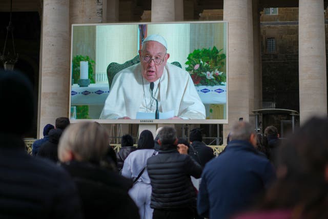 Pope Francis on big screen in front of crowd of people