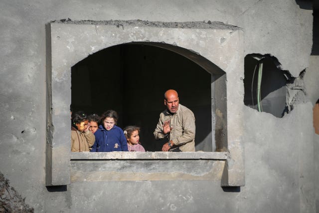 Man and children at window of damaged building