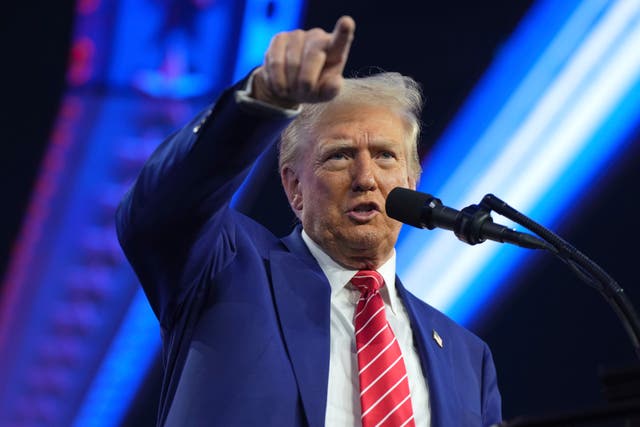 Donald Trump pointing while speaking into a microphone