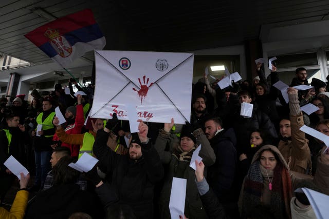 Students shouting slogans and holding a banner with a red handprint on it during a protest