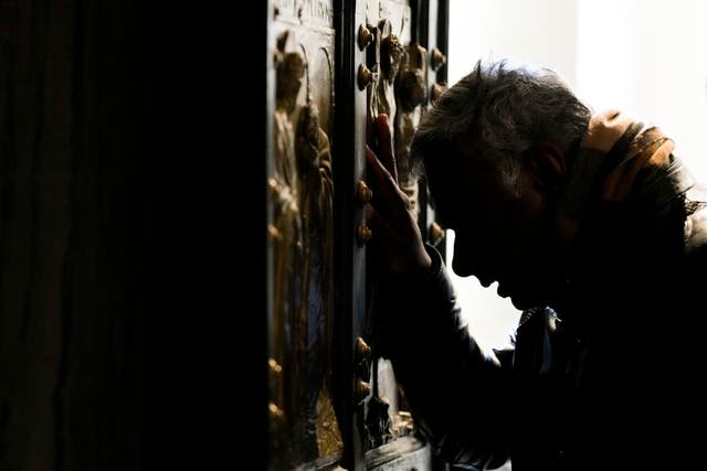 A man stops in prayer as he walks through the Holy Door of St Peter’s Basilica at the Vatican