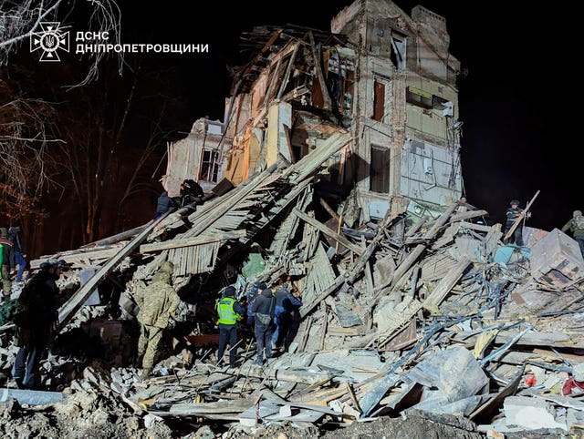 Ukrainian firefighters at a destroyed apartment building