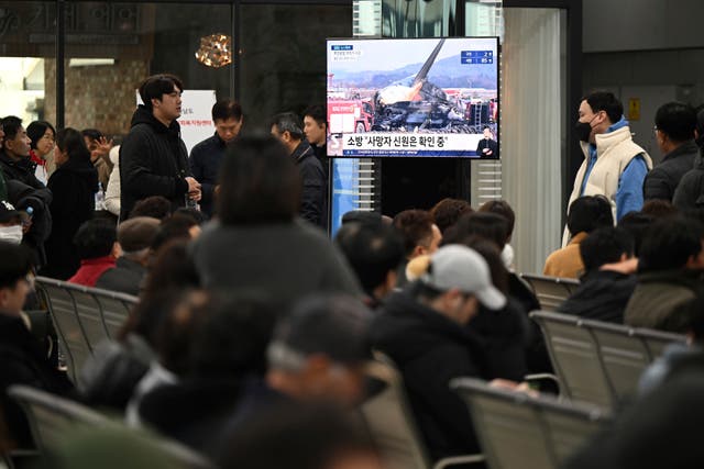 Family members of the passengers on a plane which burst into flames watch a TV news programme at Muan International Airport