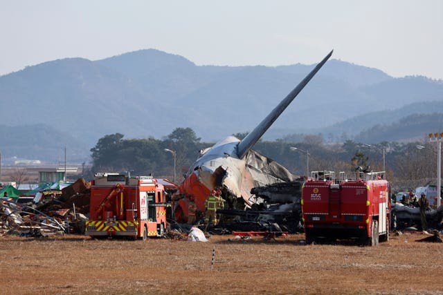 Firefighters and rescue team members work at the scene of the fire