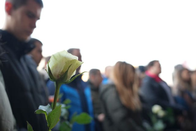 Students hold white flowers in front of the court building