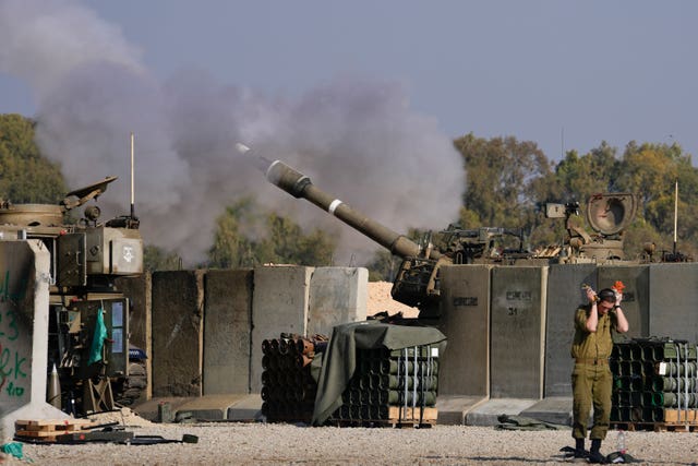 An Israeli soldier covers his ears as an artillery gunner fires into the Gaza Strip from a position in southern Israe