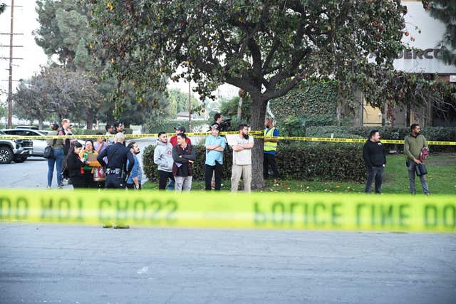 Workers stand near police lines at the scene of a plane crash in Fullerton, Southern California