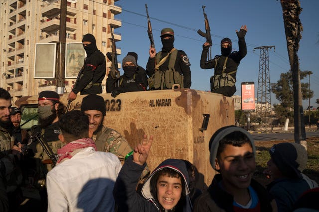 Members of the security forces of the newly formed Syrian government on a truck holding guns