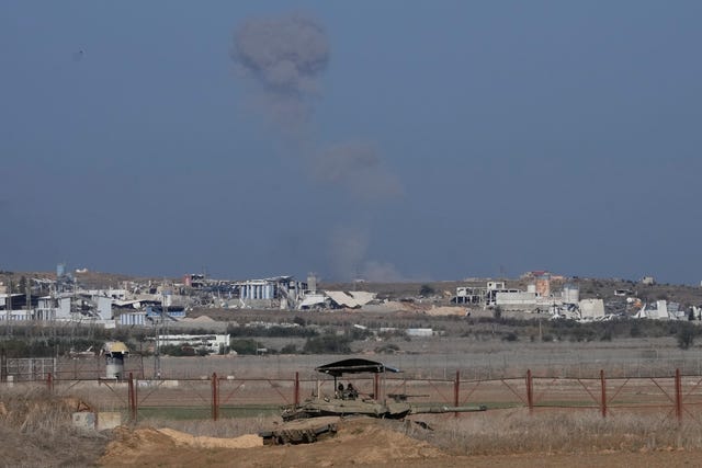 An Israeli tank sits on the Israeli-Gaza border, with a cloud of smoke inside the Gaza Strip in the background