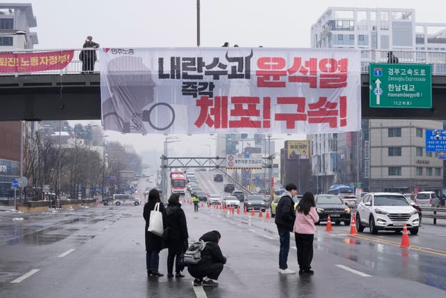 A banner is displayed on the overpass during a rally demanding the President's arrest 