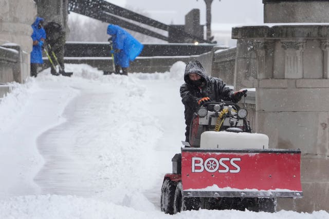 Workers clear snow from a walkway 