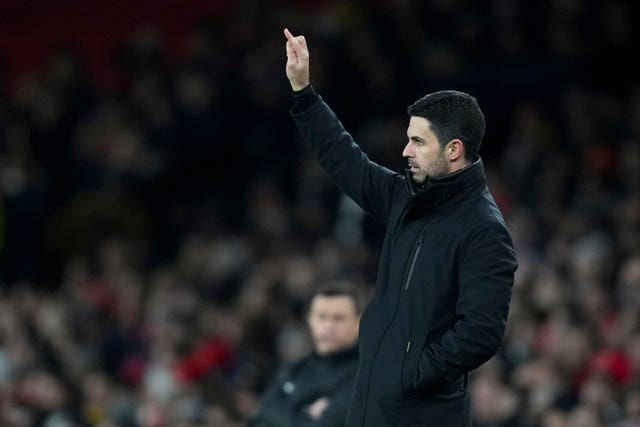 Mikel Arteta holds up his right arm on the touchline