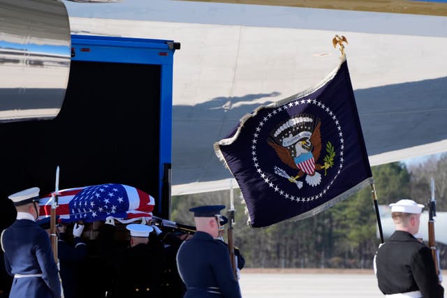 The flag-draped casket of former president Jimmy Carter is placed onto Special Air Mission 39