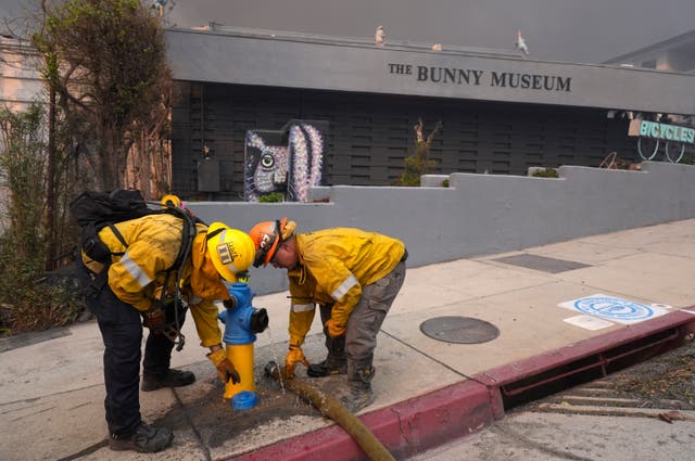 Firefighters working a hydrant in front of the burning Bunny Museum