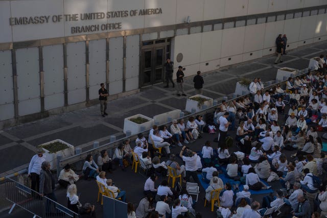 Protesters sit in front of the US Embassy branch office in Tel Aviv, Israel