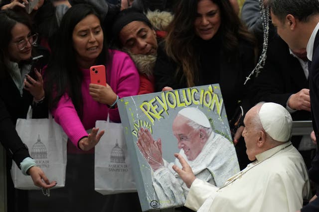 Pope Francis passes in front of a painting with his portrait 