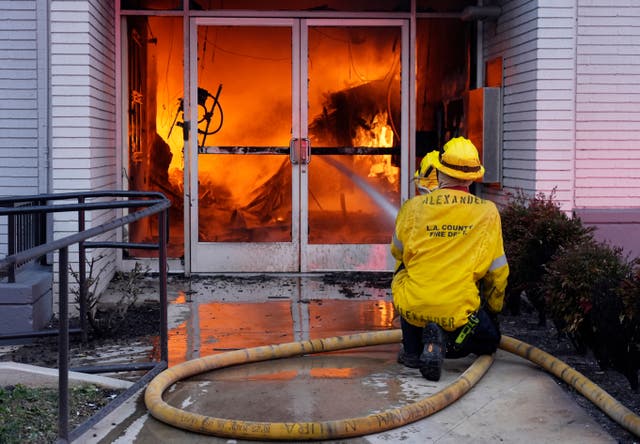 Firefighters aim a hose at the entrance to a Bank of America branch engulfed in flames in Pasadena