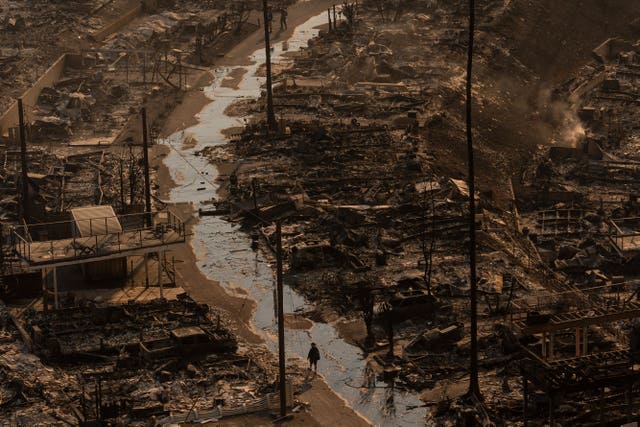 A person walks amid the destruction left behind by the Palisades Fire